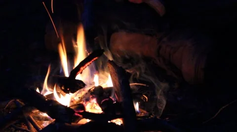 Man sitting next to a small campfire Stock Footage 44446883