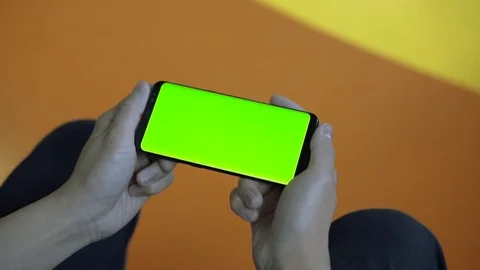 Man sitting at office holding smart phone with green screen in landscape mode Stock Footage