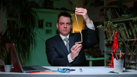 A man sitting at the office table plays with a logical toy. Vídeo Stock 128100189