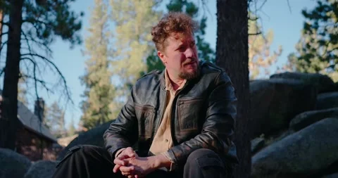Man Sitting Outdoors in Forest by Rocks Stock Footage 323349052