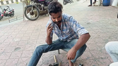 Man sitting outdoors using a mobile phone while working on a mechanical dev.. Stock Footage 267844799