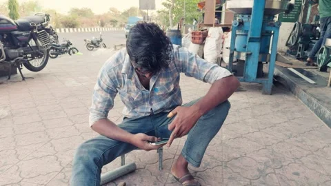Man sitting outdoors using a mobile phone while working on a mechanical dev.. Stock Footage 267849014