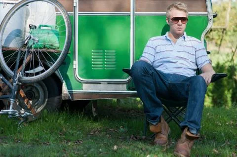 Man sitting outside trailer in park Stock Photos