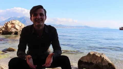 Man sitting over rock closer to rocky shore Stock Footage 83267301