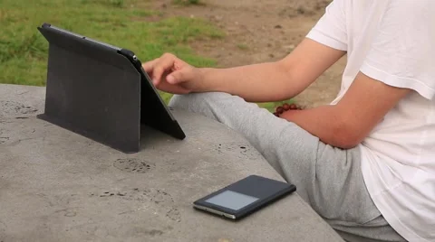 Man sitting at the park and reading a book on tablet computer in Jeju island Stockbeeldmateriaal 54315197