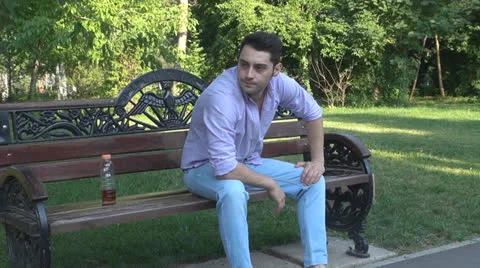 Man sitting on park bench, bored, nervous Vídeos de archivo 25562886