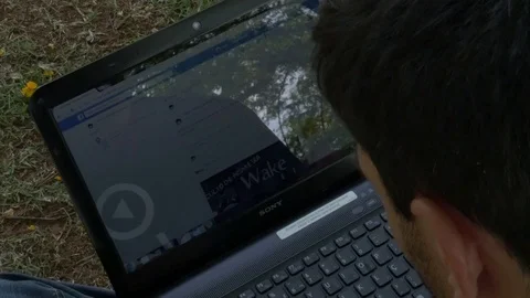 Man sitting in the park by the lake using notebook Stock Footage 70161648