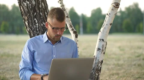 Man is Sitting at the park, Sitting on the Ground,Working with Laptop Freelance Stock Footage 68077110
