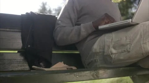 A man sitting in a park using a laptop Stock Footage 11288551