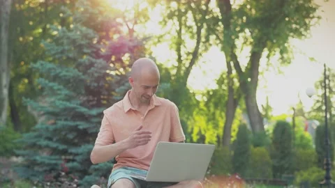 A man sitting in a park working with a laptop. Video stock 155151102