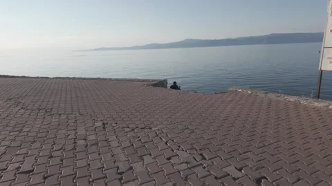 Man sitting on pavement at seaside Stock Footage 310945732