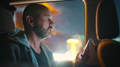 Man sitting with phone in minibus interior during evening city commute. Stock Footage 337922004