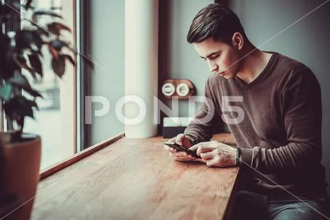 The man sitting with a phone in the restaurant Stock Photos