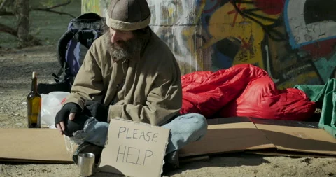 Man sitting with a please help cardboard sign while rocking back and forth Stock Footage 143469278