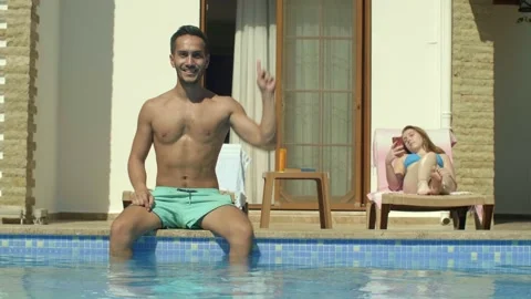 Man sitting by the pool points to the top of the screen with one finger. Stock Footage 144313983