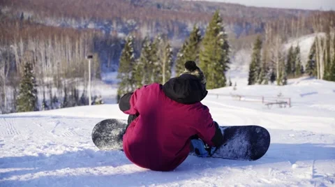 Man sitting, preparing to go snowboarding tightening Stock-Footage 66746421