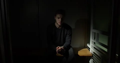 Man sitting in a prison cell in handcuffs Stock Footage 169532091
