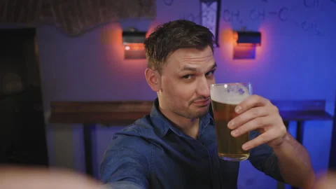 A man is sitting in a pub on bar counter, drinking beer and taking a video Stock Footage 243770004