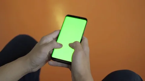 Man sitting in public space texting and typing on smart phone with green screen Stock Footage