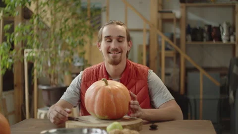 A man is sitting with a pumpkin and looking to the camera Stock Footage 170269764