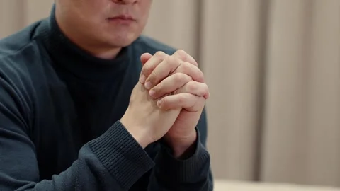Man sitting quietly with hands clasped, deep in thought at home Stock Footage 325670557