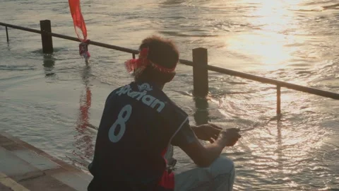 Man sitting quietly on river steps calm morning scene 스톡 동영상 332920864