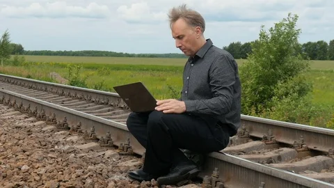 A man is sitting on the rails and working on a laptop. Stock-Footage 77232799