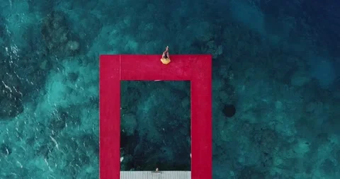 Man sitting on red pier over sea at Thulusdhoo Island in Kaafu Atoll, Maldives Stock Footage 162046356
