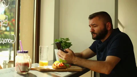 Man sitting in the restaurant and texting on smartphone Stock Footage 67992620