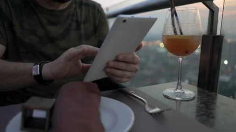 Man sitting in the restaurant on rooftop and browsing internet on tablet Stock Footage 88541053