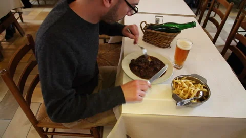 Man Sitting at Restaurant Table Eating Beef Stew with Fries and Beer 库存影片 343842645