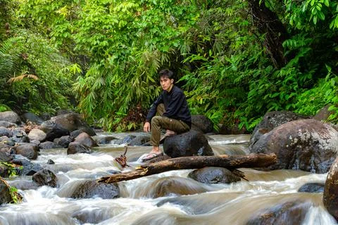 Man sitting on the river while looking around. Lonely man sitting alone in .. Stock Photos