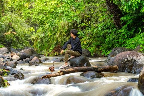 Man sitting on the river while looking around. Lonely man sitting alone in .. Stock Photos