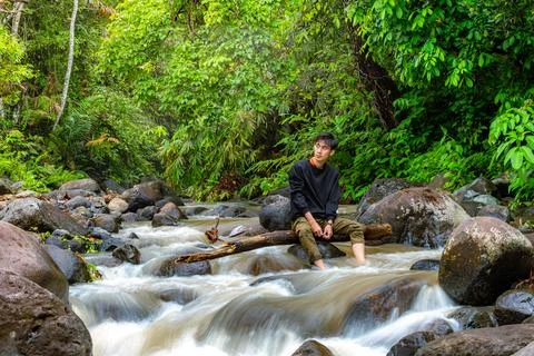 Man sitting on the river while looking around. Handsome man sitting alone i.. Stock Photos
