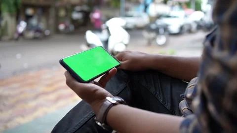 Man sitting on road side and looking at mobile phone screen, Green screen Stock Footage 246594389