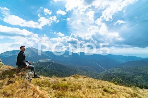 The man sitting on the rock and enjoing picturesque landscape Stock Photos
