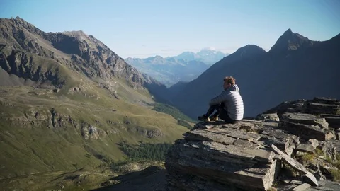 Man sitting on rock and looking at mountain panorama, 4K Stock Footage 129610788