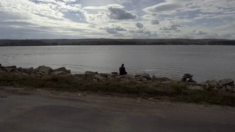 Man Sitting on Rockbed infront of Ocean Stock Footage 90932639