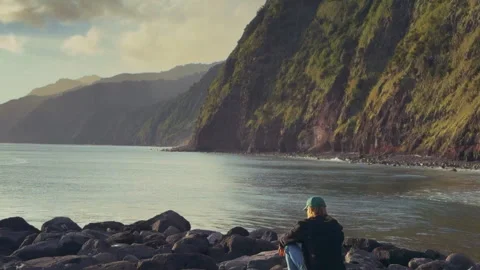 Man Sitting on Rocks by Ocean Cliffs, Azores São Miguel Island Stock Footage 316595475