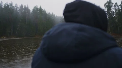 Man sitting in a rowboat on the lake inside the forest while it's raining Stock Footage 83241321