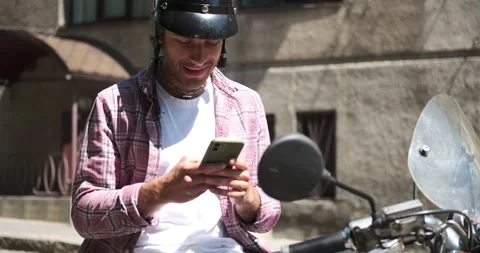 Man sitting on scooter and using mobile phone Stock Footage 136355681