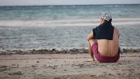 The man is sitting on the seashore 스톡 동영상 82319904