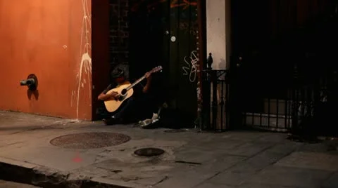 Man sitting in the shadows of street playing guitar 스톡 동영상 10795087