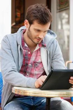 Man sitting at a sidewalk cafe using a digital tablet, Paris, Ile-de-France, Stock-Fotos