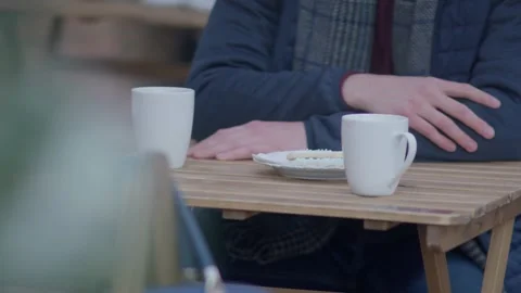 Man Sitting at Small Table Waiting With Coffee Mug and Pastry, Close-Up Stock Footage 279030751