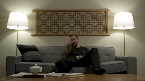 Man sitting on sofa and changing channels with remote control. Stock Footage 88175987