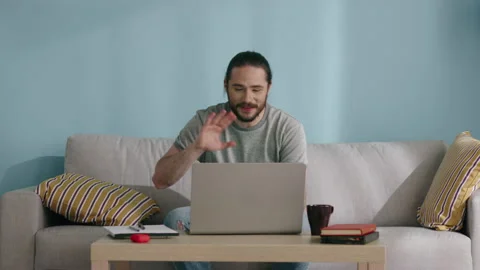 Man Is Sitting on Sofa and Communicating Online Stock Footage 130451156