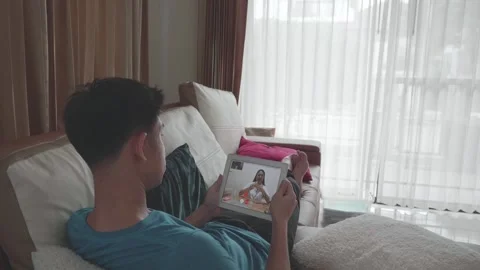 A man is sitting on sofa and make teleHealthcare call with Doctor Stock Footage 314221767