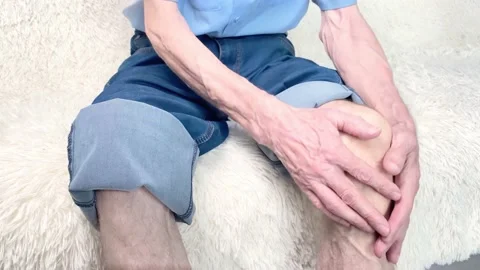 Man sitting on sofa and suffering from knee pain Stock Footage 170192142