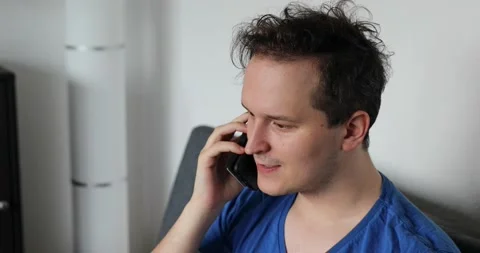 Man sitting on the sofa and talking on the smartphone Stock Footage 131161777
